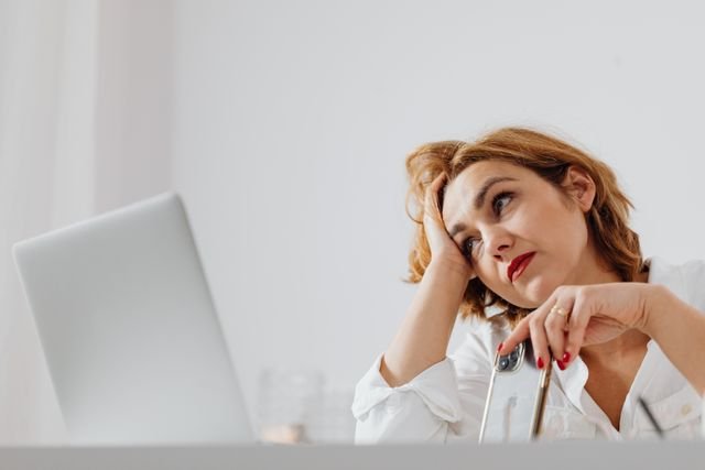 Woman over 50 losing focus under stress at her desk